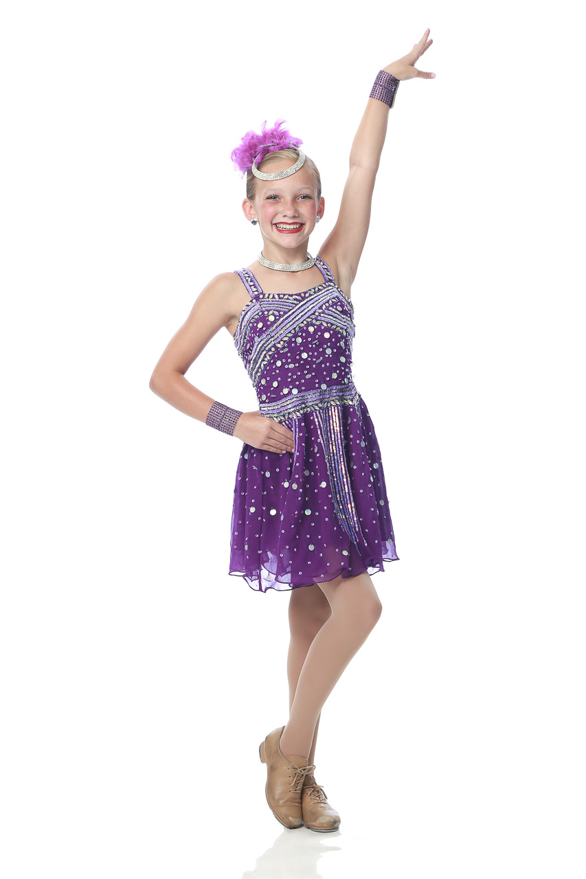 Young female dancer in purple dance costume poses with one hand on hip and the other raised for dance recital photography in Exulting Images’ Fort Mill SC studio
