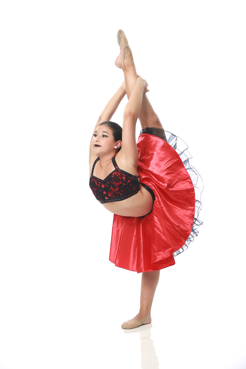 Young female dancer in red top with black lace overlay and red skirt holding a scorpion pose for dance recital photography in Exulting Images’ Fort Mill SC studio