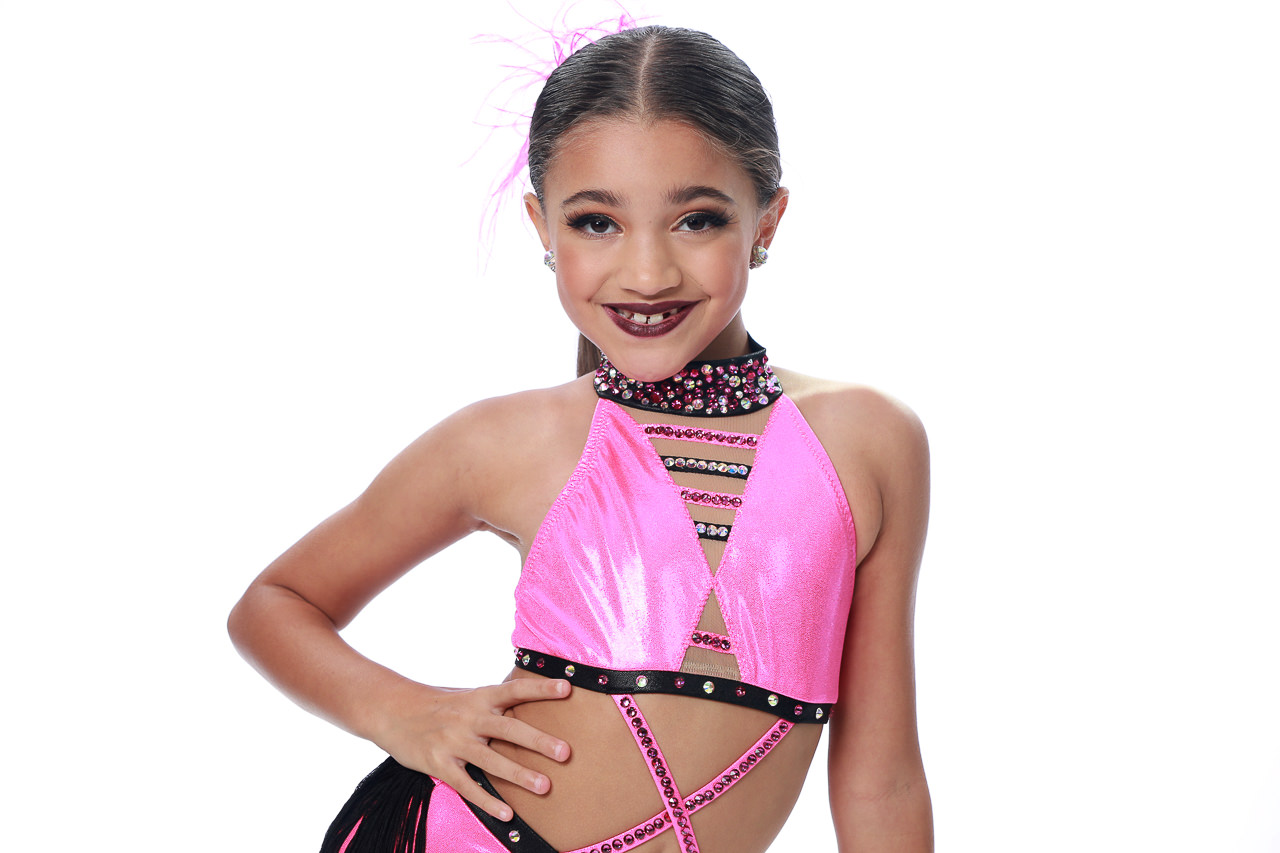 Young girl in pink dance costume with rhinestones smiles at camera for Exulting Images’ dance recital headshot