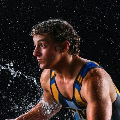Teenage male in wrestling attire surrounded by droplets of water in Exulting Images’ rain room photoshoot