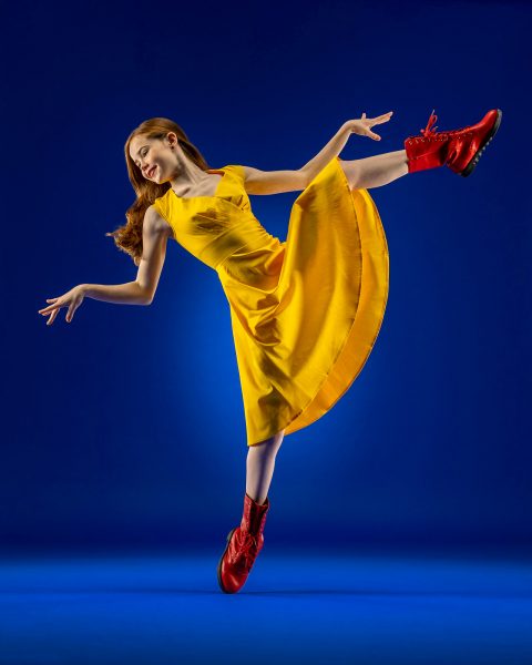 Dance action shot of Exulting Images ambassador Ceil wearing bright yellow dress and red lace up boots against dark blue background in Exulting Images’ Fort Mill, SC dance photography studio