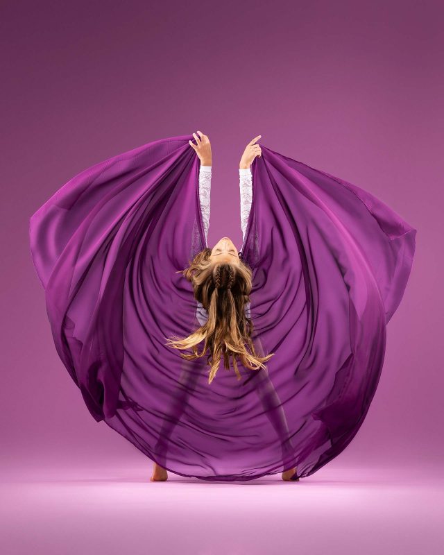 Exulting Images professional dance portrait of young girl with head tilted back and thin purple cloth spread behind her loosely grasped in her hands