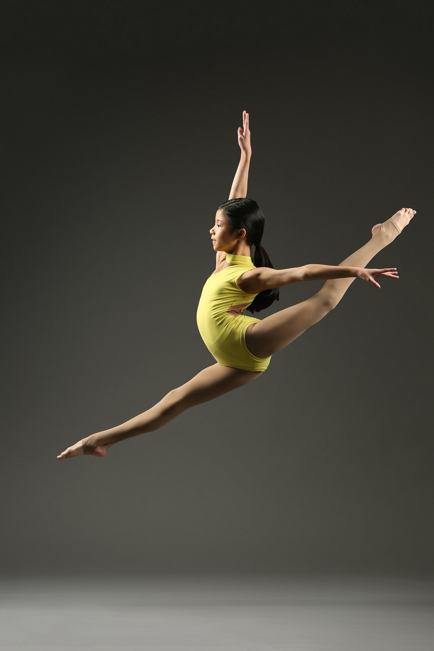 Dance action shot of young female dancer performing a grand jete