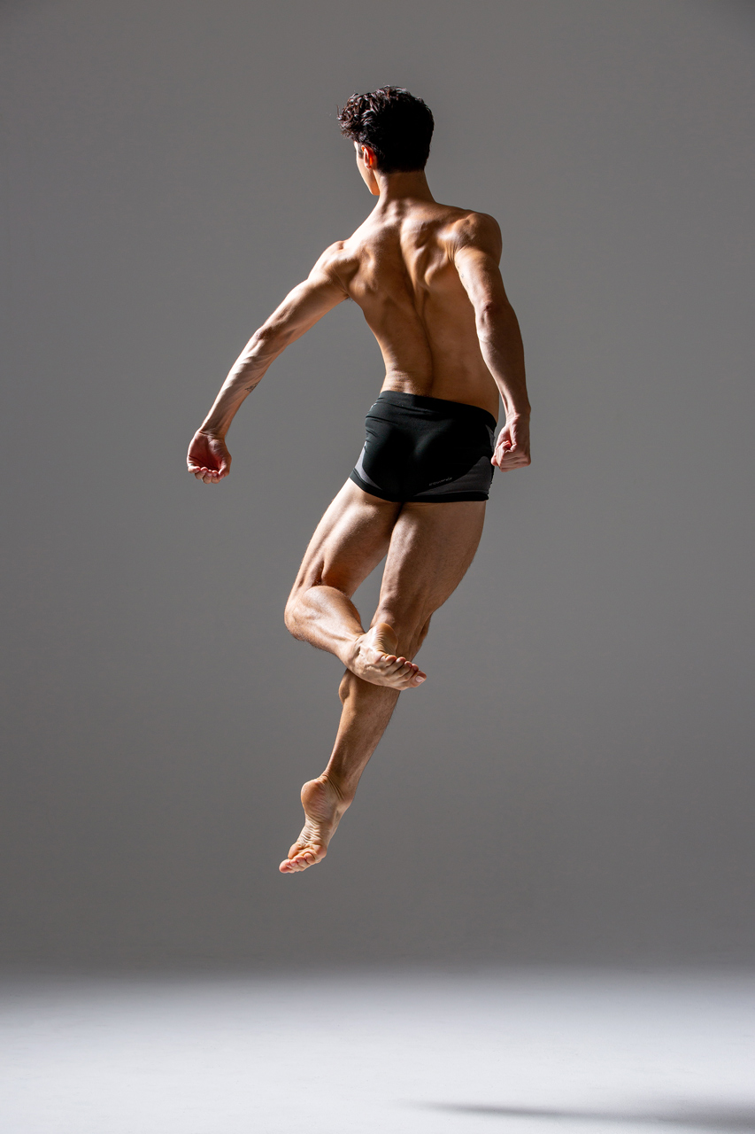 Contemporary dance photo of male dancer mid leap from the back