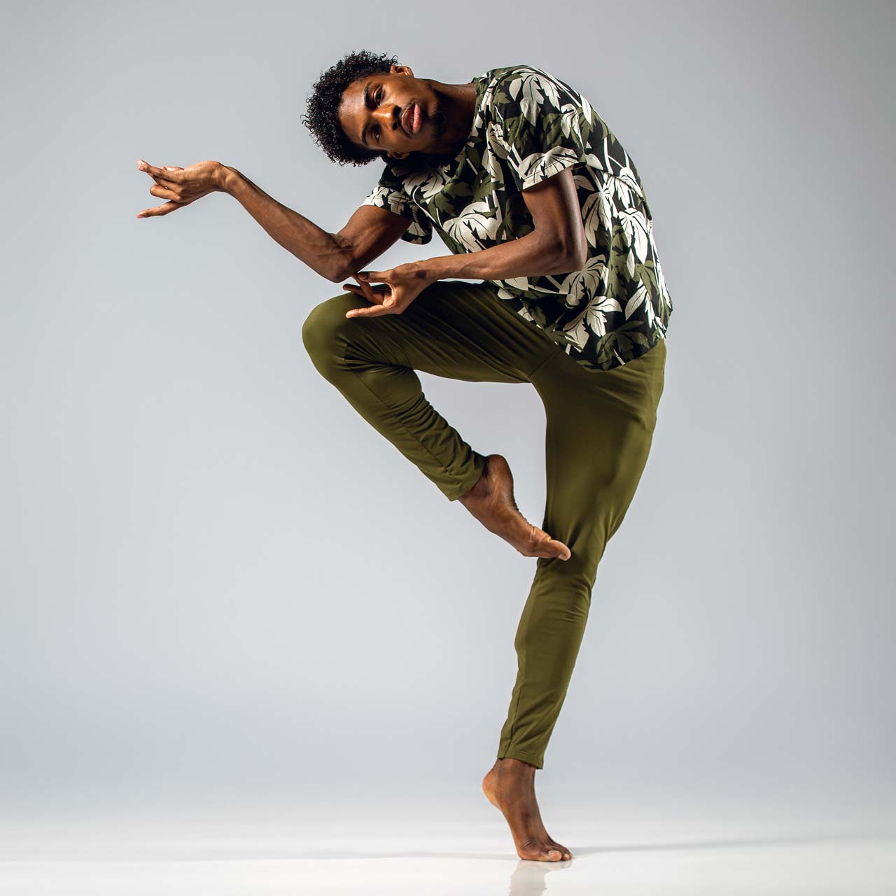 Male dancer in leaf patterned shirt and green trousers posing for contemporary dance photography in Exulting Images’ Fort Mill, SC studio