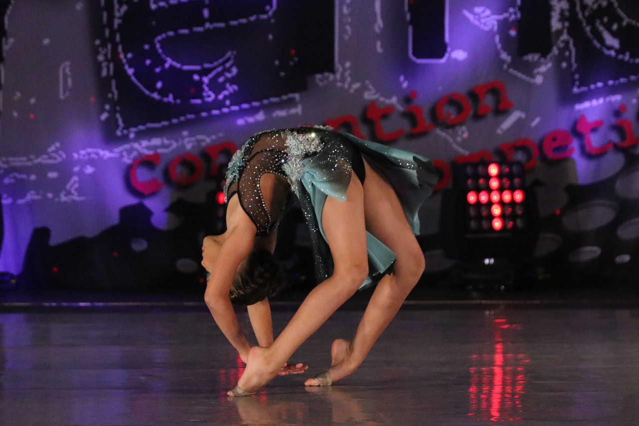 Dance competition photography by Exulting Images with young dancer in sequined costume in a back bend while balancing on the top of her feet