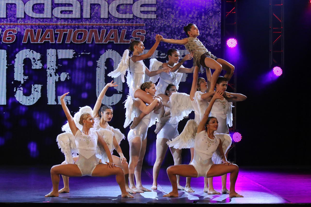 Dancers wearing white angel wings performing onstage during dance competition photographed by Exulting Images
