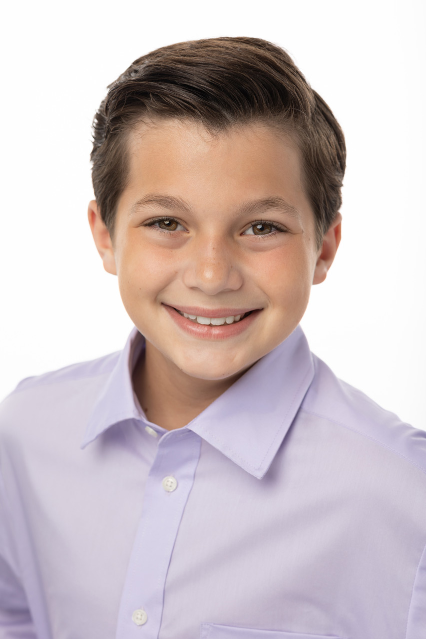 Young boy with neat brown coiffed hair smiles at camera in light colored collared shirt for Exulting Images’ dance headshot