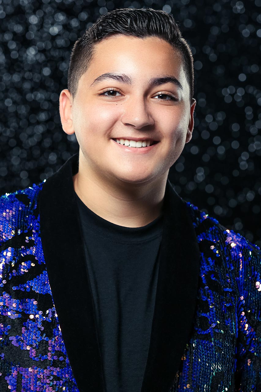 Light-skinned young man smiles at camera in blue sequin blazer for Exulting Images’ dance headshot