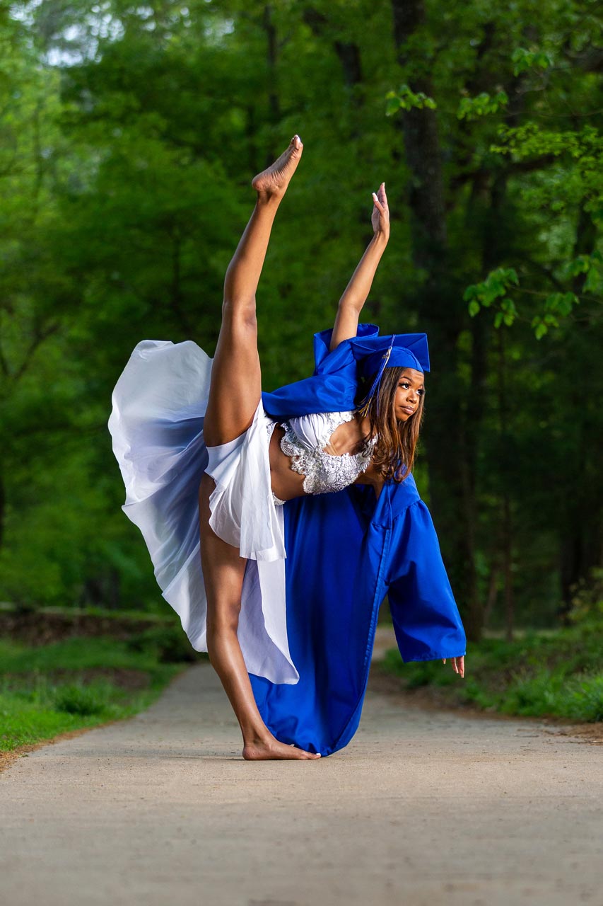 Female dancer poses in blue graduation cap and gown for outdoor dance photoshoot with Exulting Images