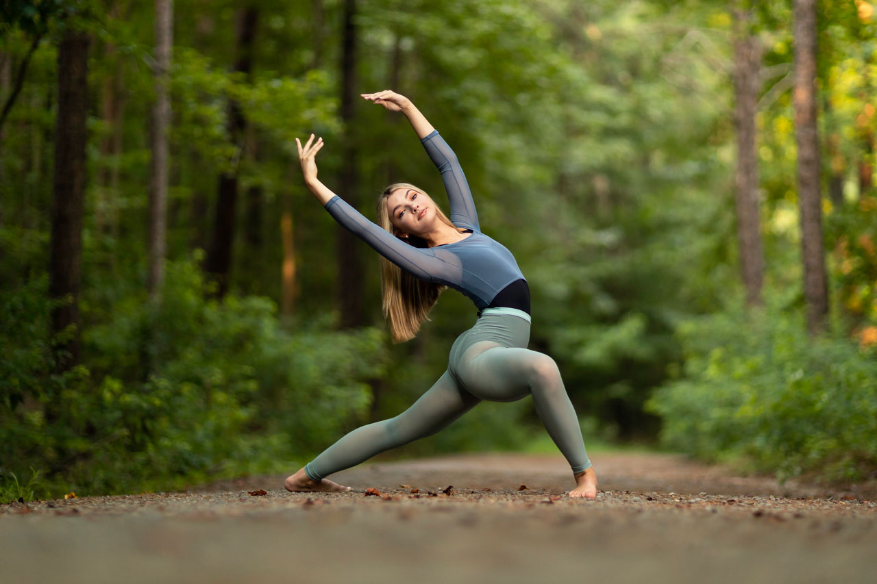 Dancer on gravel forest trail poses in a deep lunge for outdoor dance pictures with Exulting Images in Fort Mill, SC