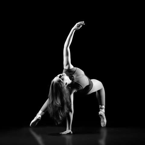Exulting Images black and white ballet portrait photography of female on pointe with one hand on ground and the other reaching gently upward