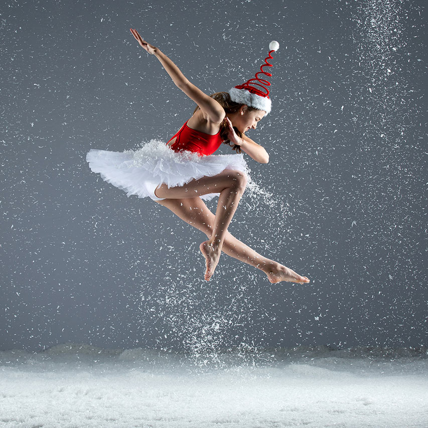 Exulting Images' dance action shot of young dancer in springy santa hat and red and white costume mid jump