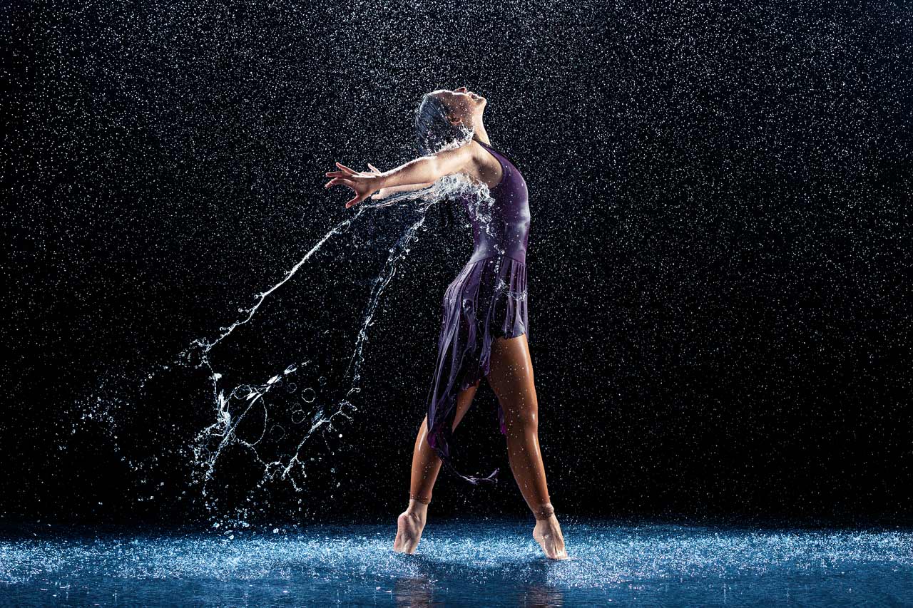 Rain drenched dancer in purple on tiptoe poses for water dance photography at Exulting Images professional dance photography in Fort Mill, SC